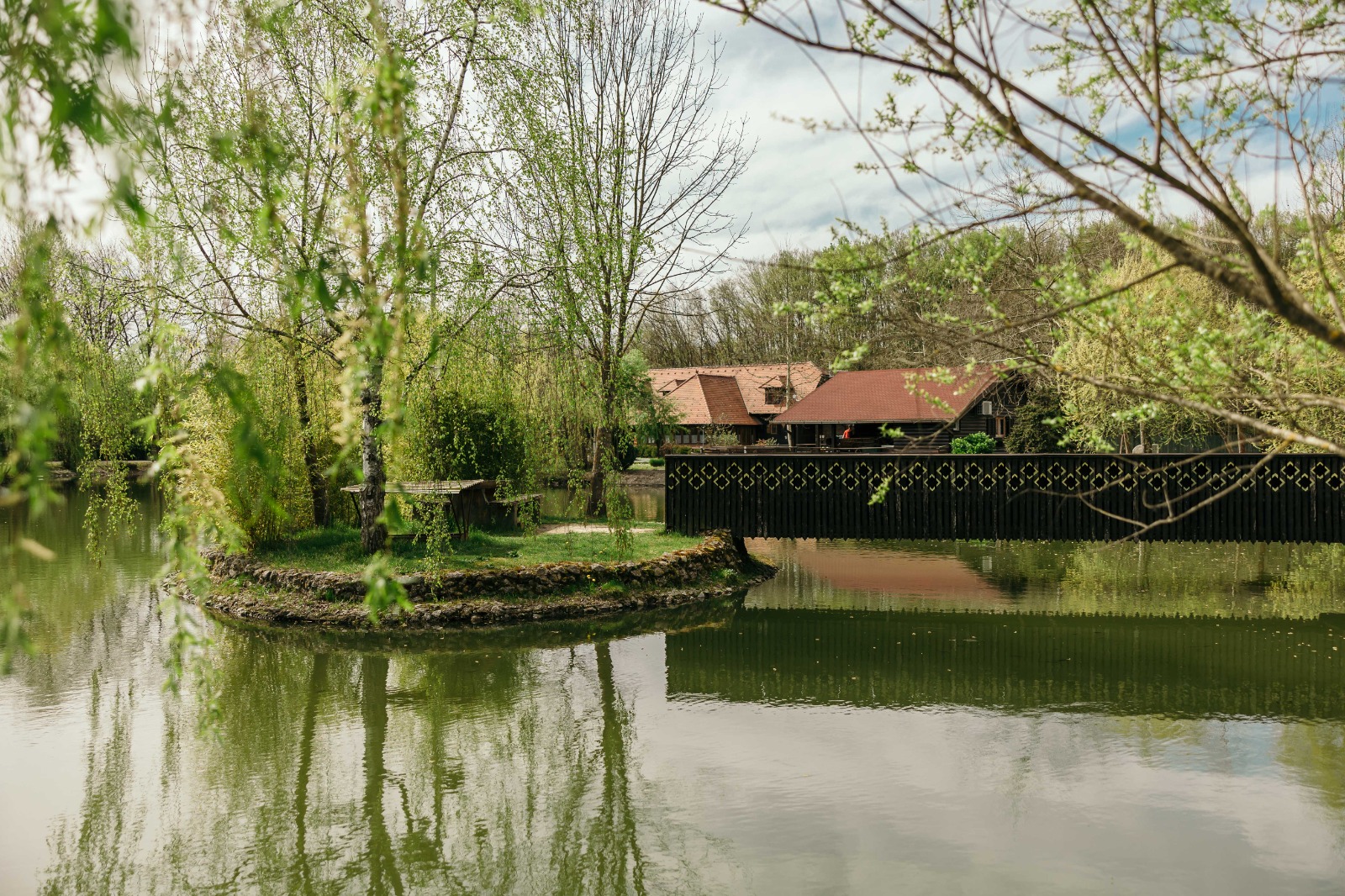 Jezero s otočićem i drvenim mostom na imanju